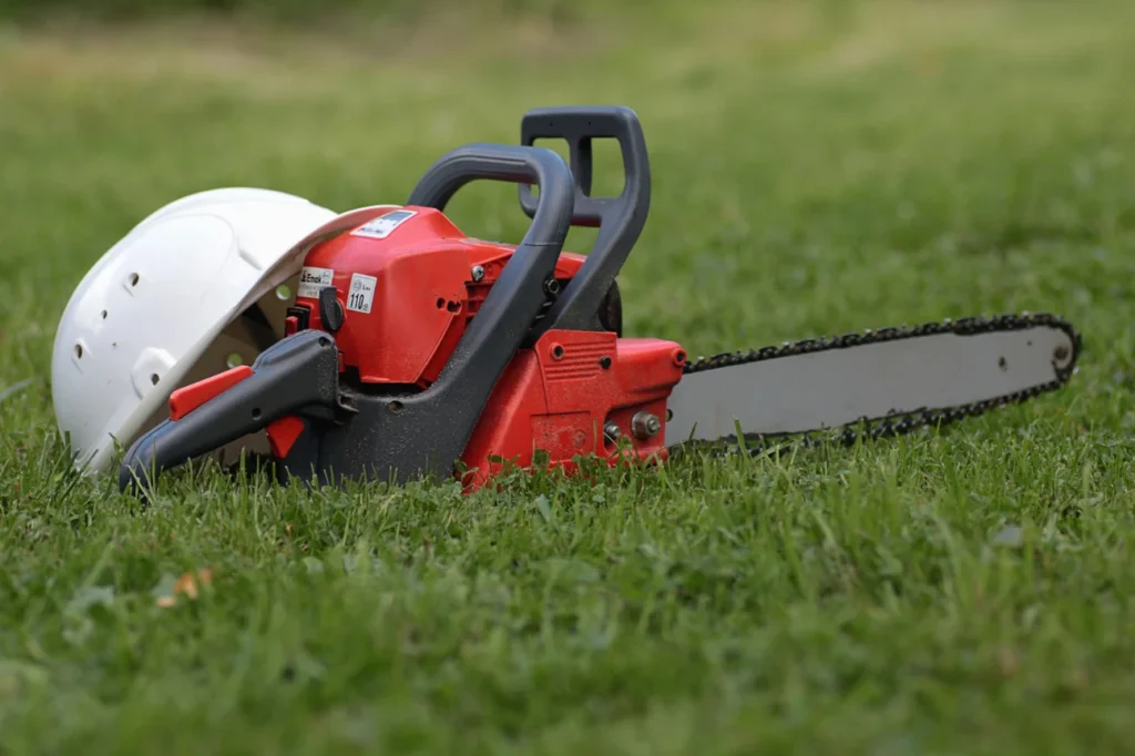 Safety equipment and chainsaw resting on grass used by Stump Grinding Auckland for privacy policy, terms and conditions, careers, newsletter, and editorial guidelines